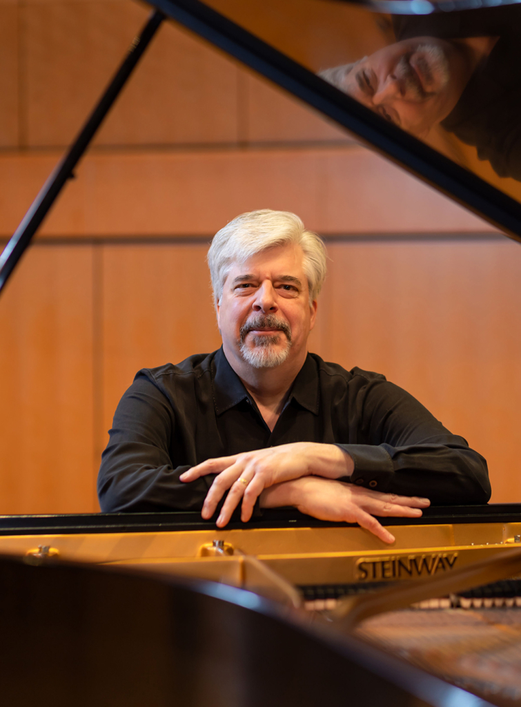 TM01web A man poses at a piano and looks at the camera